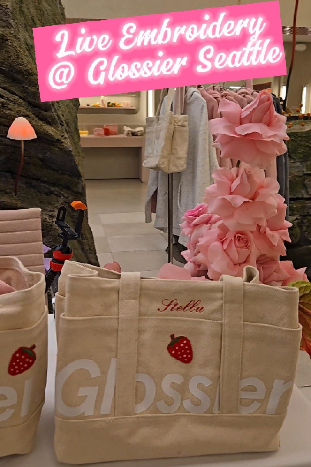 Embroidered Glossier tote bag displayed next to fresh pink roses